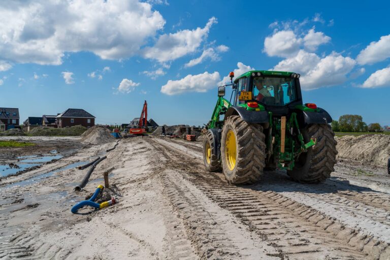 Grond wordt bouwrijp gemaakt bij 't Veld Noord met de inzet van een kraan en tractor